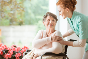 Young nurse helping an elderly woman in a wheelchair. Nursing home concept